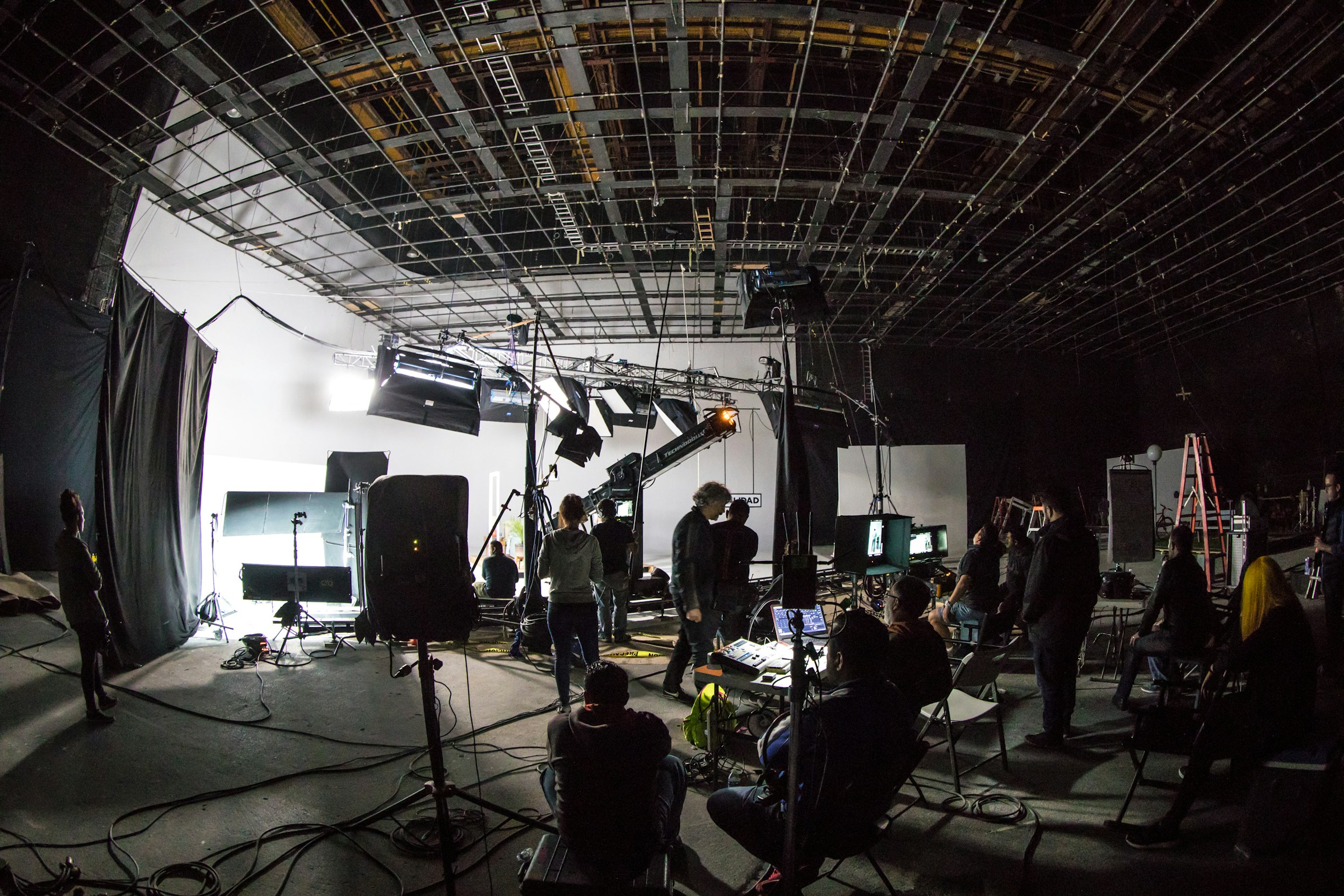 A film soundstage with crew, lighting rigs, and a cinema camera on a dolly.