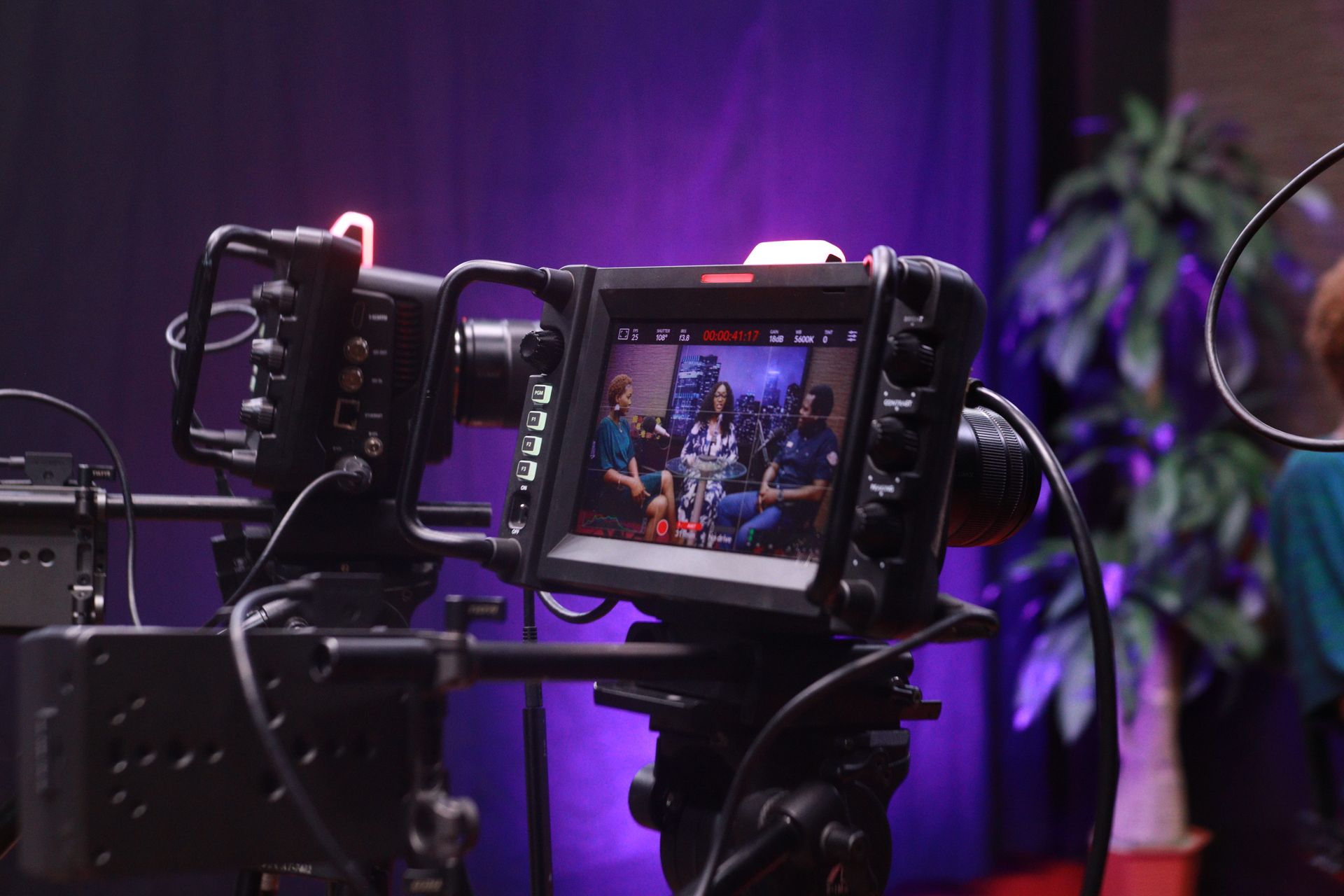 A video interview being filmed in a studio with camera and lighting equipment.