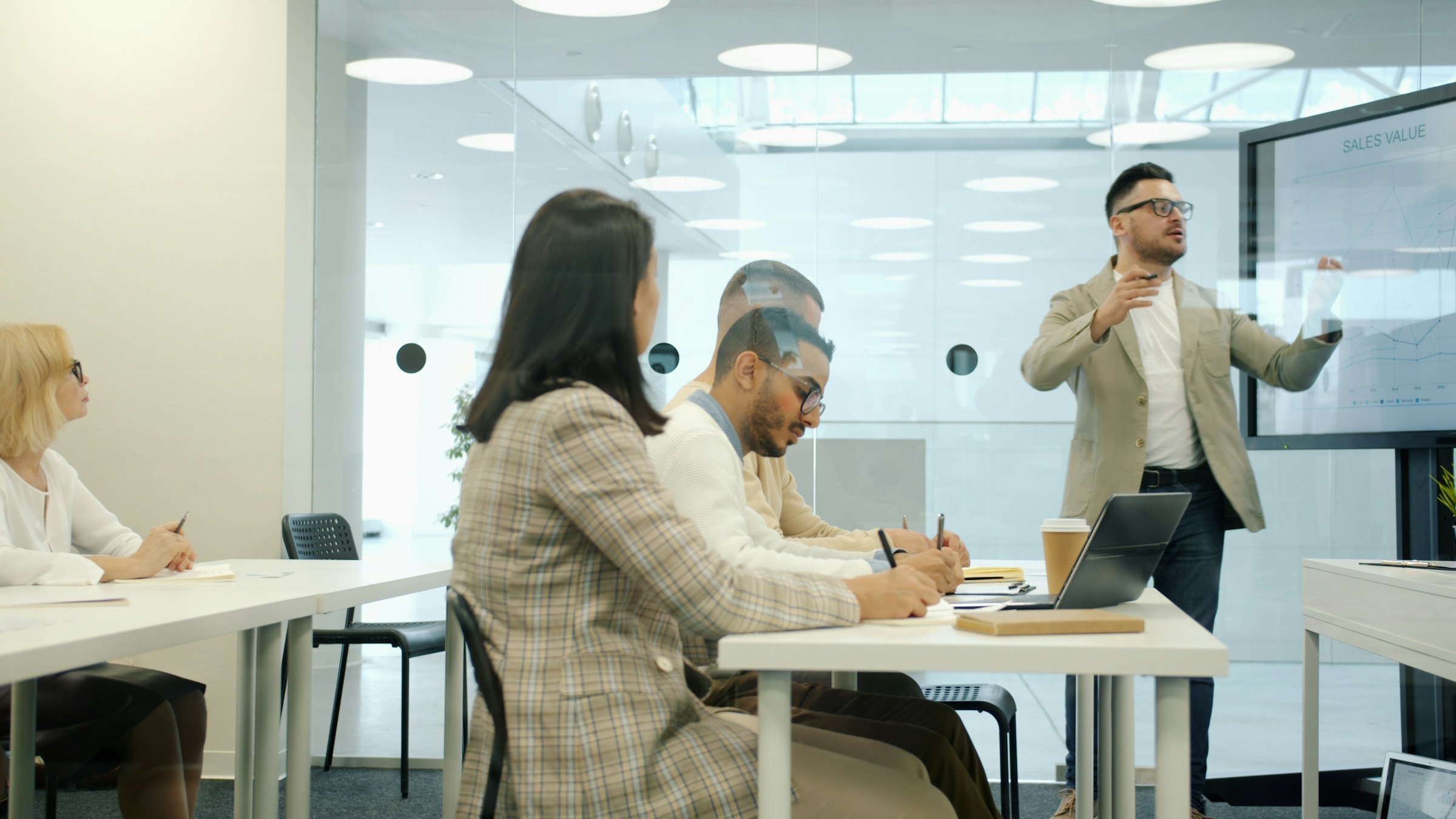 A facilitator presenting at a screen while a diverse team of colleagues review content.