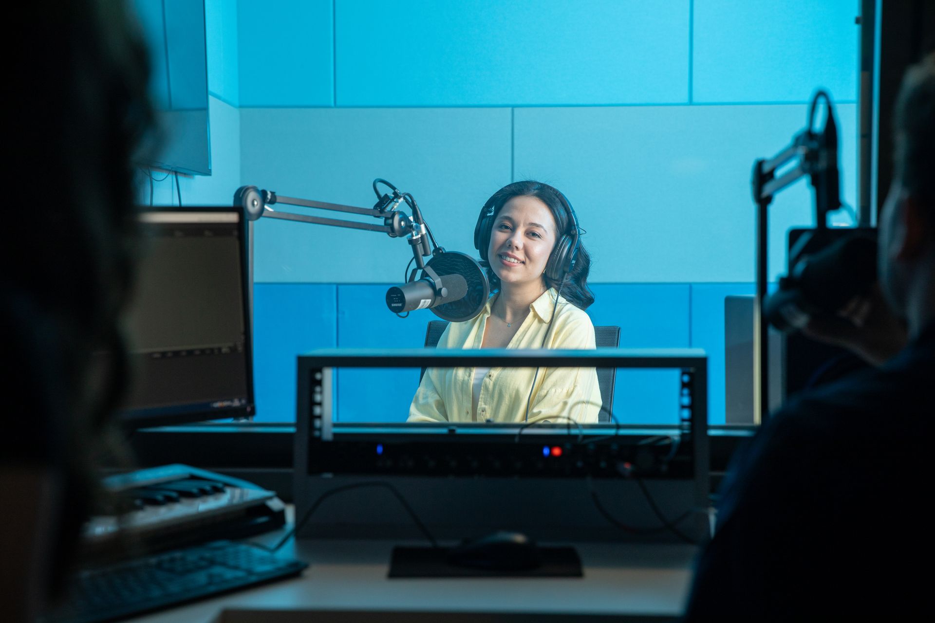 A woman speaking into a microphone while recording a podcast.
